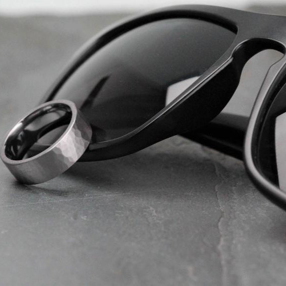 7mm wide tantalum, gunmetal colour, wedding ring resting against black sunglasses