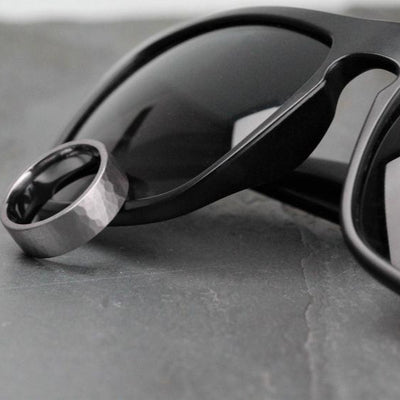 7mm wide tantalum, gunmetal colour, wedding ring resting against black sunglasses