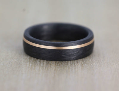 black carbon fibre wedding ring band. 6mm wide with a stripe of rose gold. black mans wedding ring uk