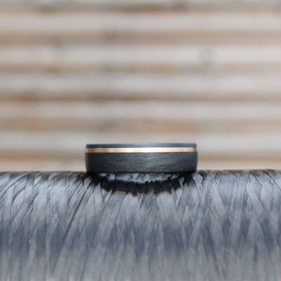 black carbon fibre wedding ring band. 6mm wide with a stripe of rose gold. black mans wedding ring uk