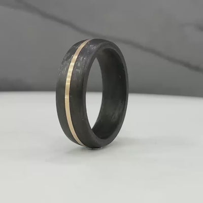 black carbon fibre wedding ring band. 6mm wide with a stripe of rose gold. black mans wedding ring uk